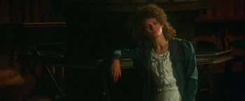 Movie still from “McCabe & Mrs. Miller” (1971), directed by Robert Altman – A woman with curly hair leaning against a wall; Medium shot, Low angle