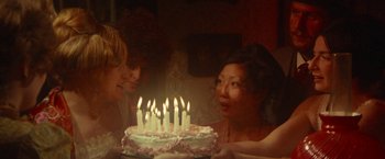 Movie still from “McCabe & Mrs. Miller” (1971), directed by Robert Altman – Two women looking at a cake with lit candles on it; Medium shot, High angle