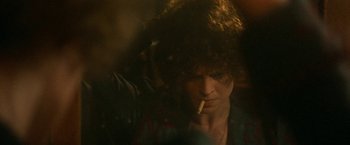 Movie still from “McCabe & Mrs. Miller” (1971), directed by Robert Altman – A man is smoking a cigarette in a dark room; Close Up shot, Over the shoulder angle