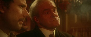 Movie still from “McCabe & Mrs. Miller” (1971), directed by Robert Altman – An older man wearing a suit and a tie; Close Up shot, Over the shoulder angle