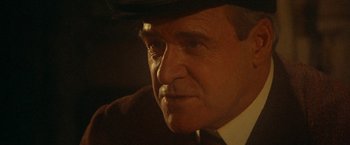 Movie still from “McCabe & Mrs. Miller” (1971), directed by Robert Altman – An older man wearing a suit and a hat; Close Up shot, Over the shoulder angle