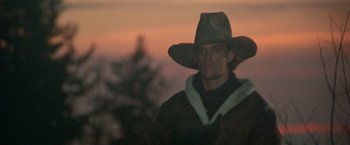 Movie still from “McCabe & Mrs. Miller” (1971), directed by Robert Altman – A man wearing a cowboy hat in front of a sunset; Close Up shot, Low angle