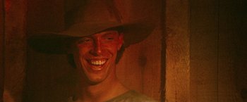 Movie still from “McCabe & Mrs. Miller” (1971), directed by Robert Altman – A man wearing a cowboy hat smiling for the camera; Close Up shot, Low angle