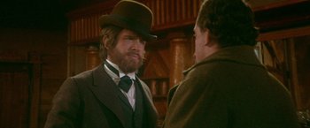 Movie still from “McCabe & Mrs. Miller” (1971), directed by Robert Altman – A man with a beard wearing a hat and a suit; Close Up shot, Over the shoulder angle