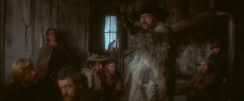 Movie still from “McCabe & Mrs. Miller” (1971), directed by Robert Altman – A group of people sitting around a room; Medium shot, Low angle