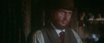 Movie still from “McCabe & Mrs. Miller” (1971), directed by Robert Altman – A man wearing a hat , vest , and tie; Close Up shot, Over the shoulder angle