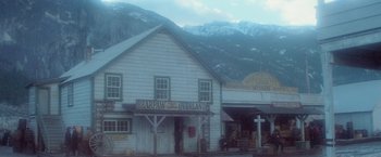 Movie still from “McCabe & Mrs. Miller” (1971), directed by Robert Altman – An old western style store with a mountain in the background; Extreme Wide shot, High angle