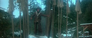 Movie still from “McCabe & Mrs. Miller” (1971), directed by Robert Altman – A man standing in the middle of a rope bridge; Wide shot, Low angle