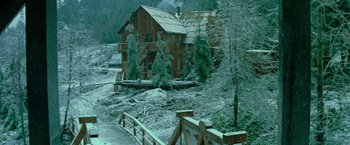 Movie still from “McCabe & Mrs. Miller” (1971), directed by Robert Altman – A log cabin with a wooden fence in front of it; Extreme Wide shot, High angle