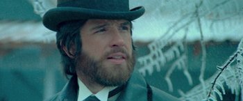 Movie still from “McCabe & Mrs. Miller” (1971), directed by Robert Altman – A man with a beard wearing a top hat; Close Up shot, Low angle