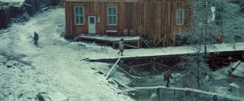 Movie still from “McCabe & Mrs. Miller” (1971), directed by Robert Altman – A person walking across a bridge in the snow; Extreme Wide shot, High angle