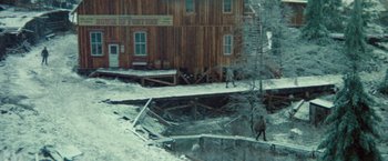 Movie still from “McCabe & Mrs. Miller” (1971), directed by Robert Altman – Two people walking on a bridge over a snow covered river; Extreme Wide shot, High angle