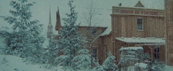 Movie still from “McCabe & Mrs. Miller” (1971), directed by Robert Altman – A snow covered tree in front of a building; Extreme Wide shot, Low angle