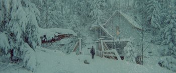 Movie still from “McCabe & Mrs. Miller” (1971), directed by Robert Altman – A person standing in the snow near a house; Extreme Wide shot, Low angle