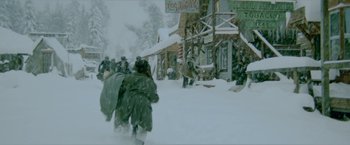 Movie still from “McCabe & Mrs. Miller” (1971), directed by Robert Altman – A group of people walking down a snow covered street; Wide shot, High angle