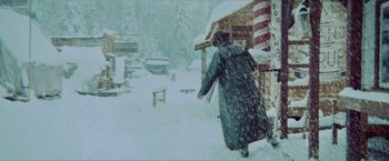 Movie still from “McCabe & Mrs. Miller” (1971), directed by Robert Altman – A person walking in the snow near a building; Wide shot, Low angle