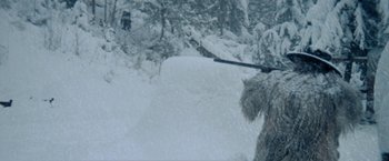 Movie still from “McCabe & Mrs. Miller” (1971), directed by Robert Altman – A person riding skis down a snow covered slope; Wide shot, Over the shoulder angle