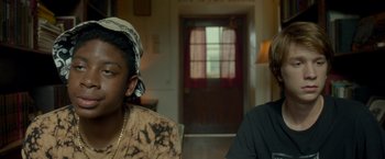 Movie still from “Me and Earl and the Dying Girl” (2015), directed by Alfonso Gomez-Rejon – A man and a woman sitting next to each other in front of a door; Close Up shot, Over the shoulder angle