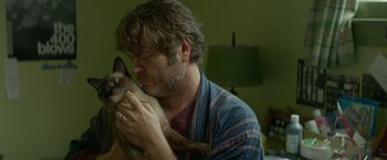 Movie still from “Me and Earl and the Dying Girl” (2015), directed by Alfonso Gomez-Rejon – A man holding a siamese cat in his arms; Close Up shot, High angle