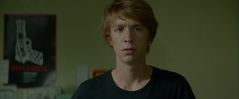 Movie still from “Me and Earl and the Dying Girl” (2015), directed by Alfonso Gomez-Rejon – A young man in a black t - shirt is looking at the camera; Close Up shot, Low angle