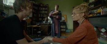 Movie still from “Me and Earl and the Dying Girl” (2015), directed by Alfonso Gomez-Rejon – A man and a woman are in a living room; Medium shot, Over the shoulder angle