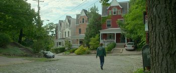 Movie still from “Me and Earl and the Dying Girl” (2015), directed by Alfonso Gomez-Rejon – A person walking down the street in front of a row of houses; Extreme Wide shot, High angle