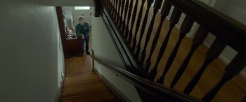 Movie still from “Me and Earl and the Dying Girl” (2015), directed by Alfonso Gomez-Rejon – A man standing in front of a wooden staircase; Wide shot, Overhead angle