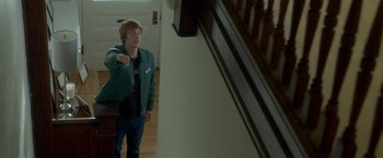 Movie still from “Me and Earl and the Dying Girl” (2015), directed by Alfonso Gomez-Rejon – A man standing in front of a staircase pointing to the ground; Medium shot, Over the shoulder angle