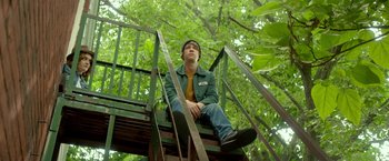 Movie still from “Me and Earl and the Dying Girl” (2015), directed by Alfonso Gomez-Rejon – A man sitting on top of a wooden staircase; Medium shot, Low angle