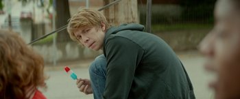 Movie still from “Me and Earl and the Dying Girl” (2015), directed by Alfonso Gomez-Rejon – A man sitting on the ground holding a tooth brush; Medium shot, Over the shoulder angle