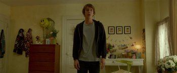 Movie still from “Me and Earl and the Dying Girl” (2015), directed by Alfonso Gomez-Rejon – A young man standing in a room with his hands in his pockets; Medium shot, Low angle