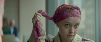 Movie still from “Me and Earl and the Dying Girl” (2015), directed by Alfonso Gomez-Rejon – A woman is holding a scarf around her head; Close Up shot, Over the shoulder angle