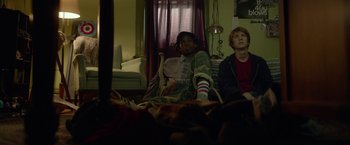 Movie still from “Me and Earl and the Dying Girl” (2015), directed by Alfonso Gomez-Rejon – Two people sitting in a living room watching television; Medium shot, Low angle