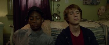 Movie still from “Me and Earl and the Dying Girl” (2015), directed by Alfonso Gomez-Rejon – Two young men sitting next to each other in a living room; Close Up shot, Low angle