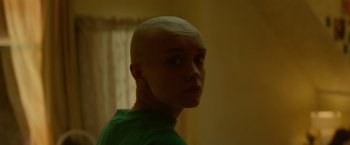 Movie still from “Me and Earl and the Dying Girl” (2015), directed by Alfonso Gomez-Rejon – A person with a shaved head is standing in a room; Close Up shot, Over the shoulder angle
