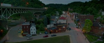 Movie still from “Me and Earl and the Dying Girl” (2015), directed by Alfonso Gomez-Rejon – An aerial view of a city at night with cars parked on the side of the road; Extreme Wide shot, High angle