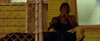 Movie still from “Me and Earl and the Dying Girl” (2015), directed by Alfonso Gomez-Rejon – A man standing in front of a chain link fence holding a cell phone to his ear; Close Up shot, Low angle