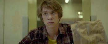 Movie still from “Me and Earl and the Dying Girl” (2015), directed by Alfonso Gomez-Rejon – A young man in a plaid shirt looking at the camera; Close Up shot, Over the shoulder angle