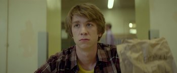Movie still from “Me and Earl and the Dying Girl” (2015), directed by Alfonso Gomez-Rejon – A young man in a checkered shirt looks at the camera; Close Up shot, Over the shoulder angle