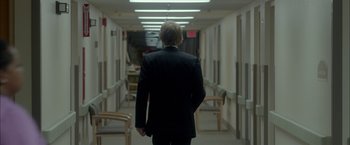 Movie still from “Me and Earl and the Dying Girl” (2015), directed by Alfonso Gomez-Rejon – A man in a black suit walking down a hall way; Medium shot, Over the shoulder angle
