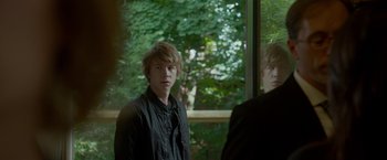 Movie still from “Me and Earl and the Dying Girl” (2015), directed by Alfonso Gomez-Rejon – A young man standing in front of a window; Medium shot, Over the shoulder angle
