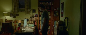 Movie still from “Me and Earl and the Dying Girl” (2015), directed by Alfonso Gomez-Rejon – A man standing in front of a computer in a room; Medium shot, Over the shoulder angle