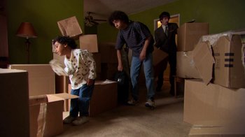 Movie still from “Me and You and Everyone We Know” (2005), directed by Miranda July – A group of young men moving boxes in a living room; Wide shot, High angle