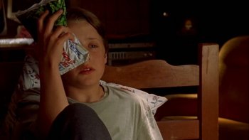 Movie still from “Mean Creek” (2004), directed by Jacob Estes – A young boy sitting on a chair holding a bag of chips; Close Up shot, High angle