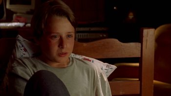Movie still from “Mean Creek” (2004), directed by Jacob Estes – A young boy sitting on a wooden bench; Close Up shot, High angle