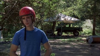Movie still from “Mean Creek” (2004), directed by Jacob Estes – A young man wearing a helmet stands in a wooded area; Medium shot, Over the shoulder angle