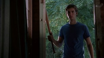 Movie still from “Mean Creek” (2004), directed by Jacob Estes – A young man holding a baseball bat near a window; Medium shot, Over the shoulder angle