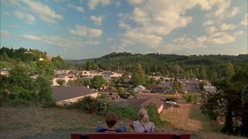 Two people sitting on a bench looking out over a town