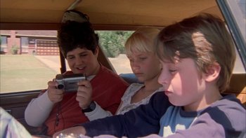 Movie still from “Mean Creek” (2004), directed by Jacob Estes – Three children sitting in the back of a car looking at a camera; Close Up shot, High angle
