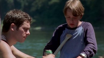 Movie still from “Mean Creek” (2004), directed by Jacob Estes – A man and a boy in the water with a baseball bat; Medium shot, Over the shoulder angle